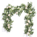 Artificial white rose and eucalyptus garland draped on a white background