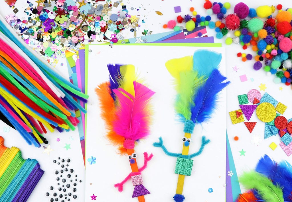 Arts and crafts supplies kit for kids, featuring pipe cleaners, pom poms, googly eyes, feathers, foam stickers, and popsicle sticks arranged on a white surface.