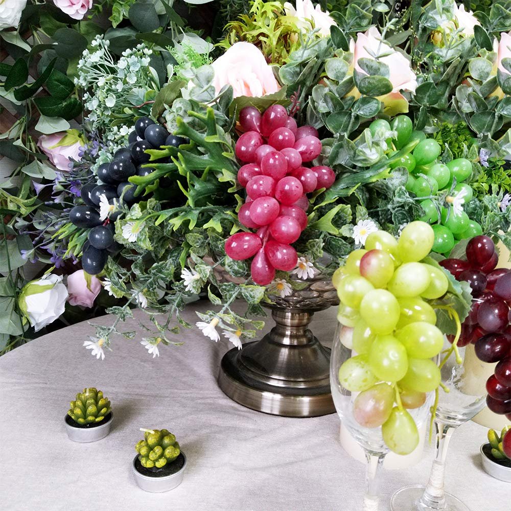 Assorted frosted artificial grape clusters in various colors arranged with faux flowers and greenery.