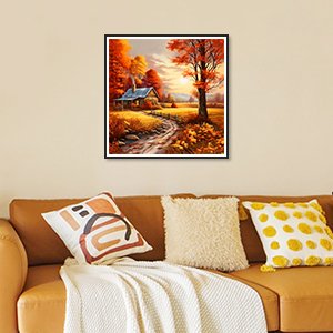 Framed autumn landscape diamond painting kit hanging above a sofa with decorative pillows.