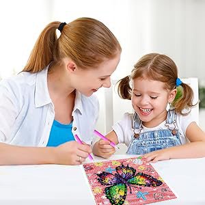 Mother and daughter smiling while doing a diamond art painting kit with a butterfly design.