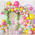 Birthday party scene with a large balloon arch, cake, and decorative blocks.