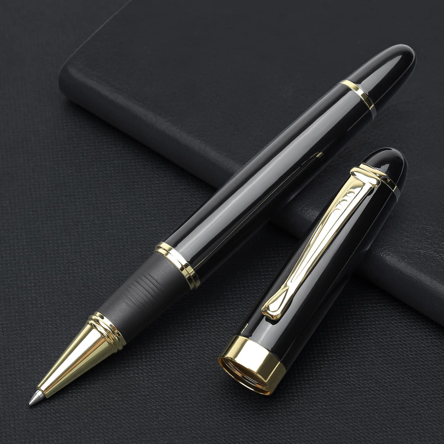Black and gold metal ballpoint pen with cap removed, lying on a dark textured surface.