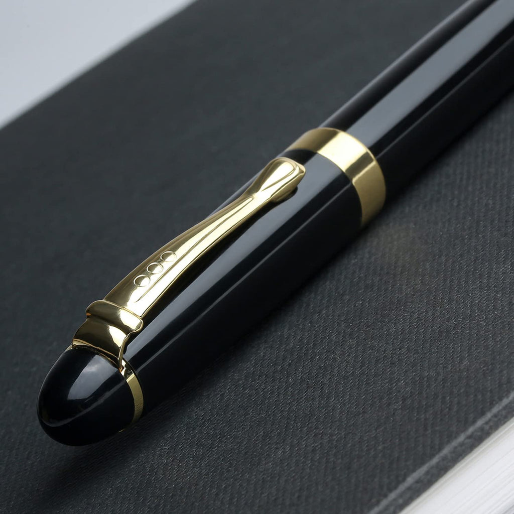 Close-up of a black metal ballpoint pen with gold accents resting on a dark textured surface.