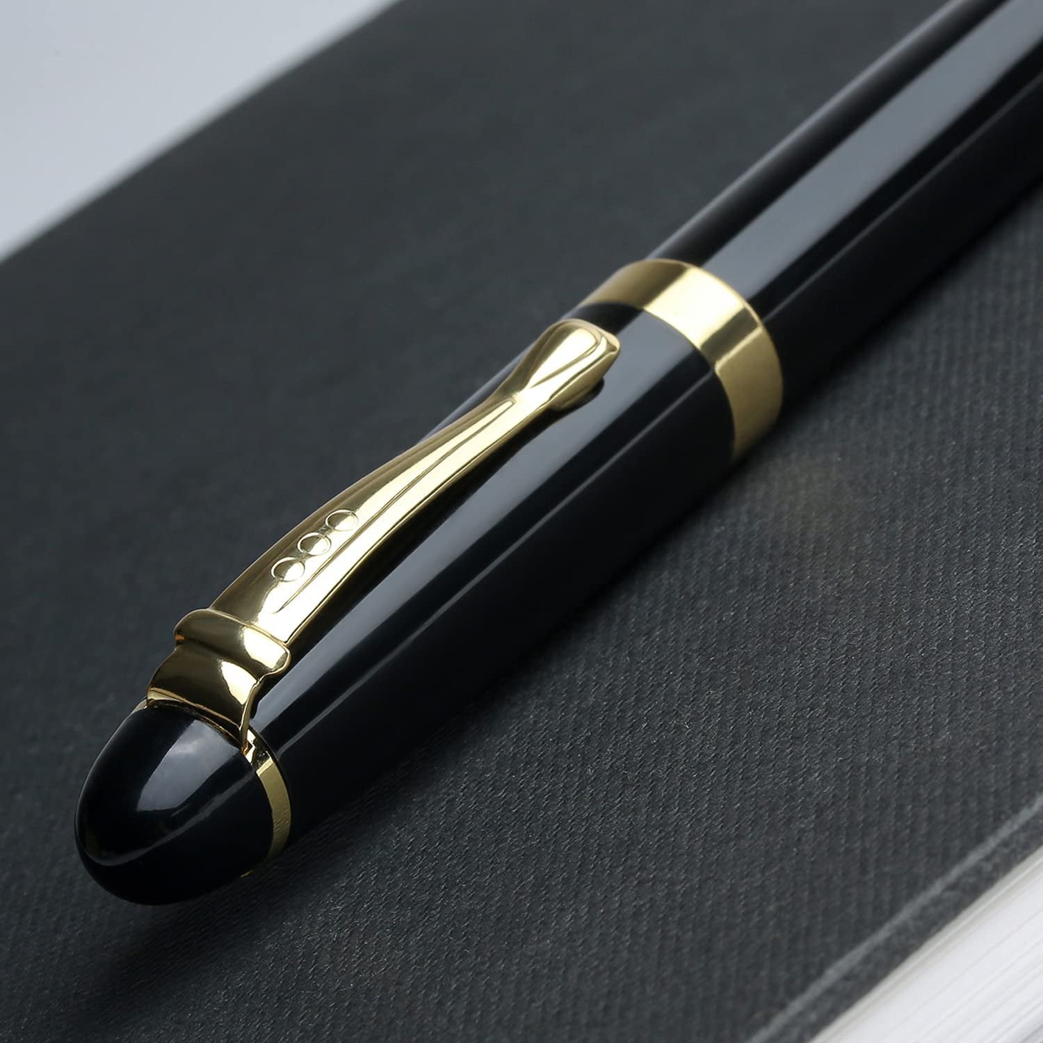Close-up of a black metal ballpoint pen with gold accents resting on a dark textured surface.