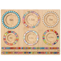Bamboo bead board for jewelry making with six bracelet sizing grooves and two ruler markings, displaying various beaded bracelets.