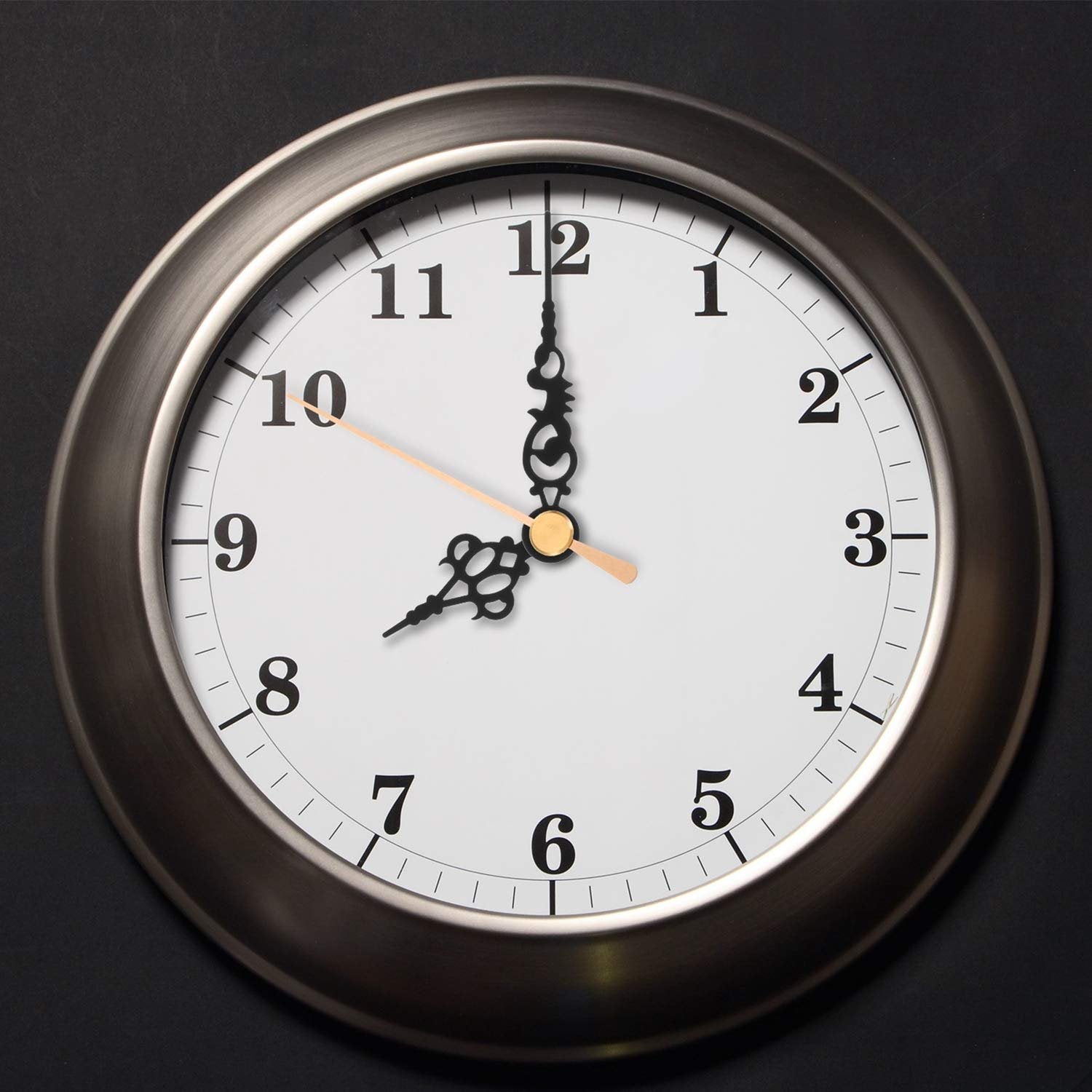 Close-up of a round analog clock face with black numbers and hands against a dark background.