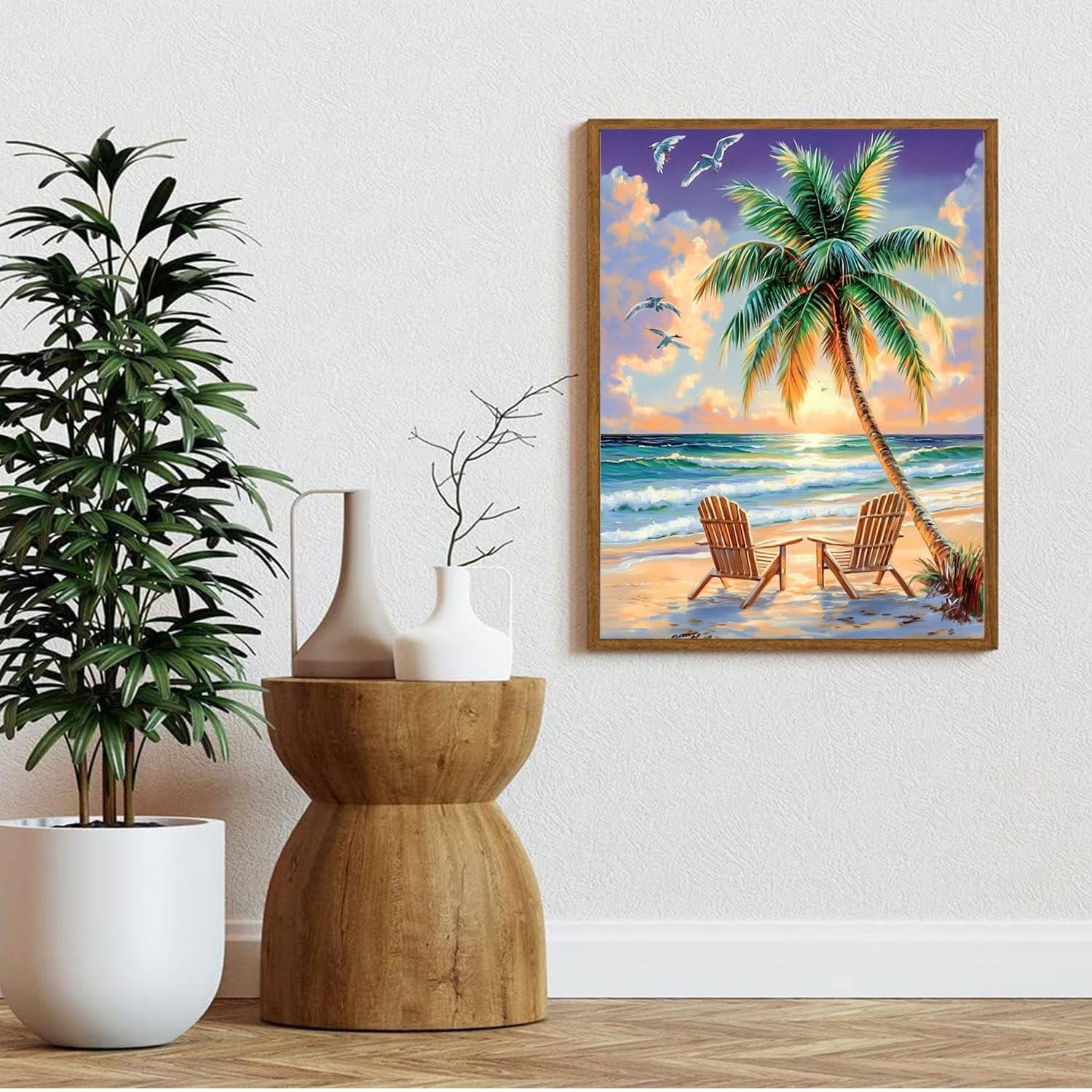 Diamond painting of a beach scene with a palm tree and two chairs, framed and hanging on a wall.