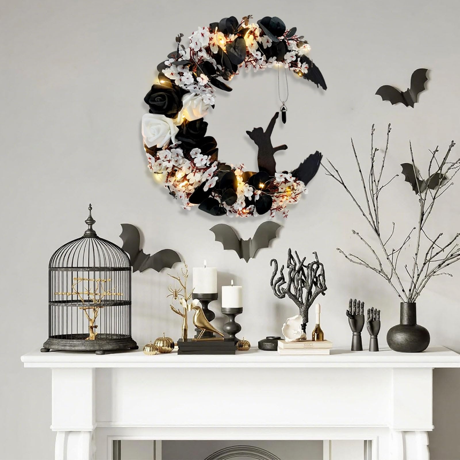 Halloween crescent moon wreath with black cat and lights, displayed on a mantel with decorative items.