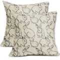Two linen pillow covers with a black sketch pattern of various Easter bunnies on a white background.
