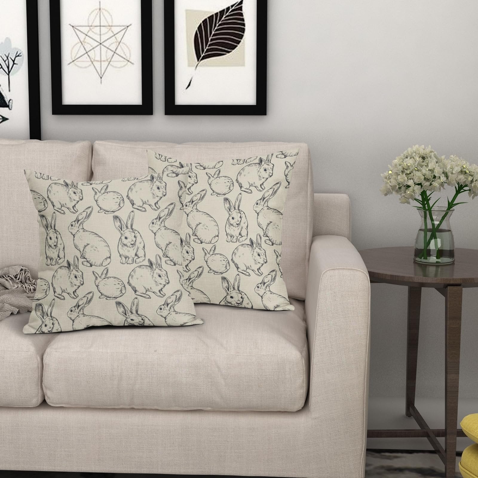 Two linen throw pillow covers with a black Easter bunny sketch pattern on a sofa.