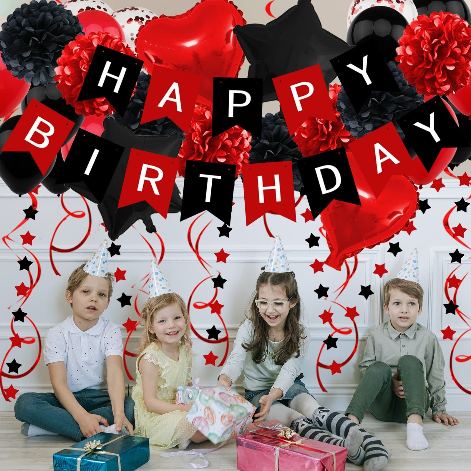 Four children in party hats sit on the floor with birthday decorations and gifts. A banner reads 'Happy Birthday'.