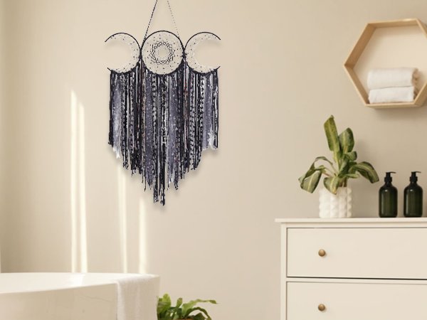 Black triple moon macrame wall hanging with crescent dream catchers and mixed textile fringe, displayed in a bathroom setting.
