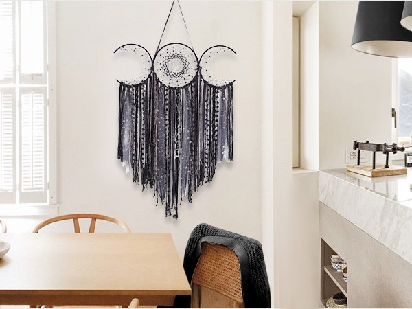 Black triple moon macrame wall hanging with crescent dream catchers and textile fringe, displayed on a white wall.