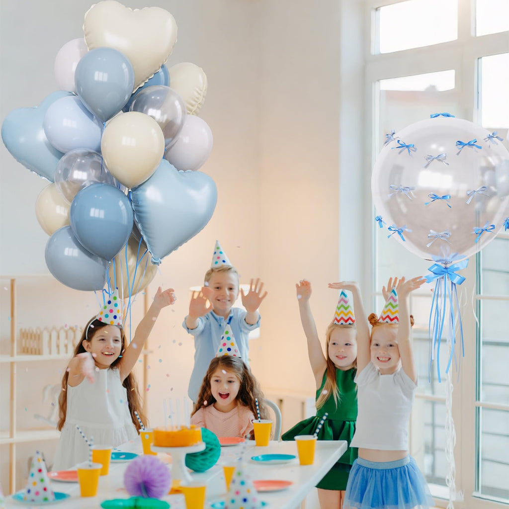 Children celebrating a birthday party with blue and nude balloons, foil hearts, and a clear balloon with bows.