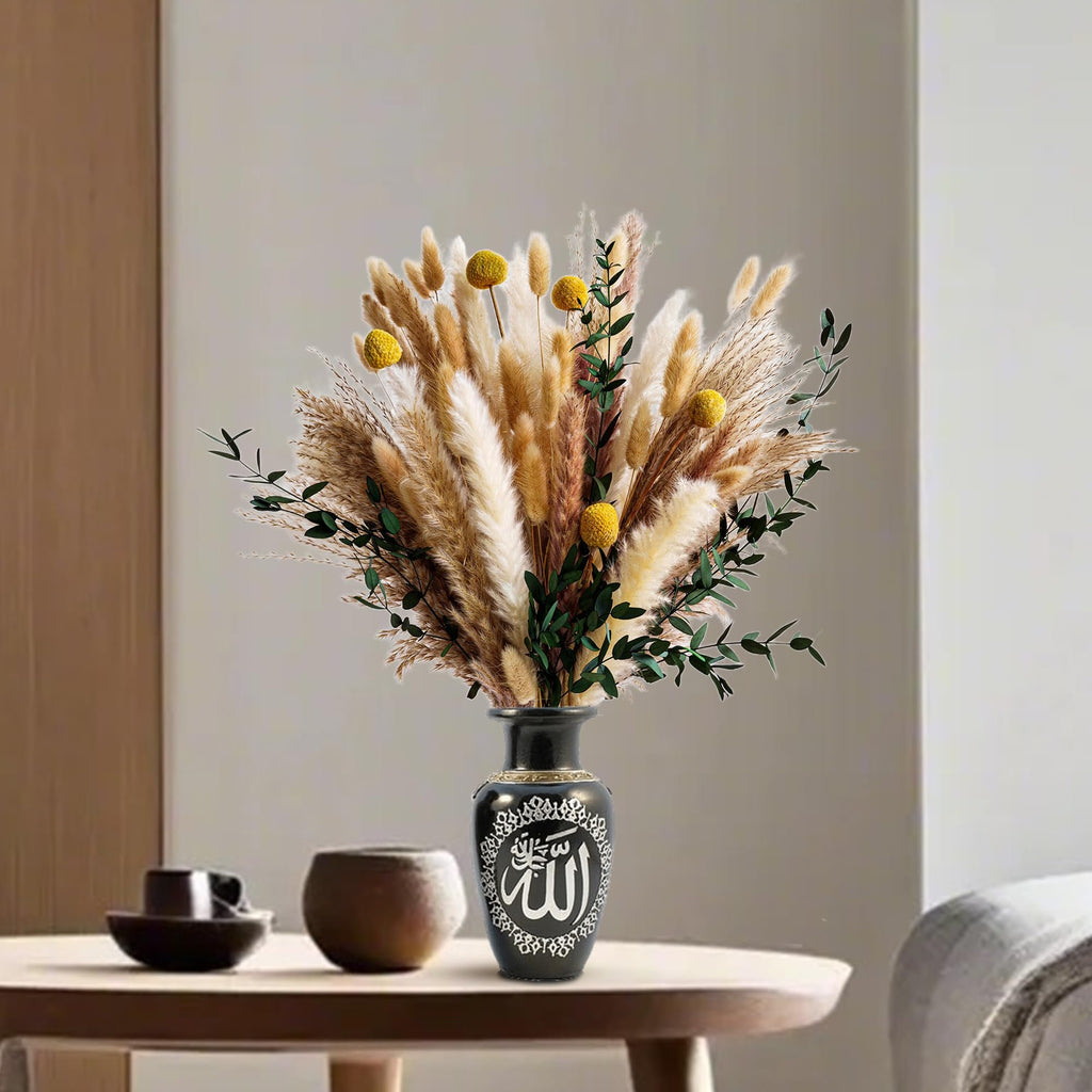 Boho dried flower bouquet with pampas grass and yellow craspedia in a decorative black vase on a table.