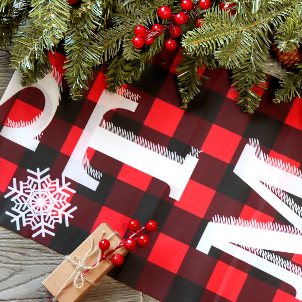 Buffalo plaid Christmas banner with white text and snowflake, decorated with pine garland and berries.