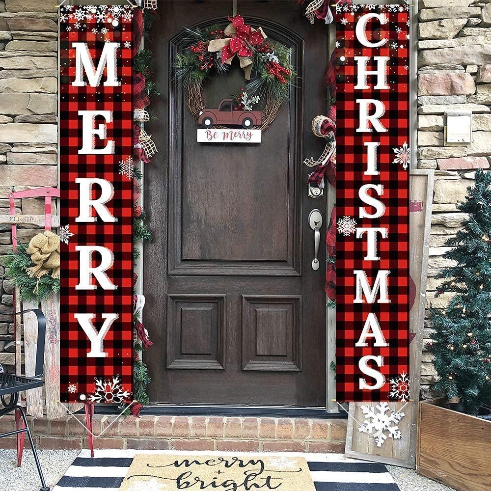 Buffalo plaid porch banners spelling MERRY CHRISTMAS flanking a wooden door with a wreath and a 'Be Merry' sign.