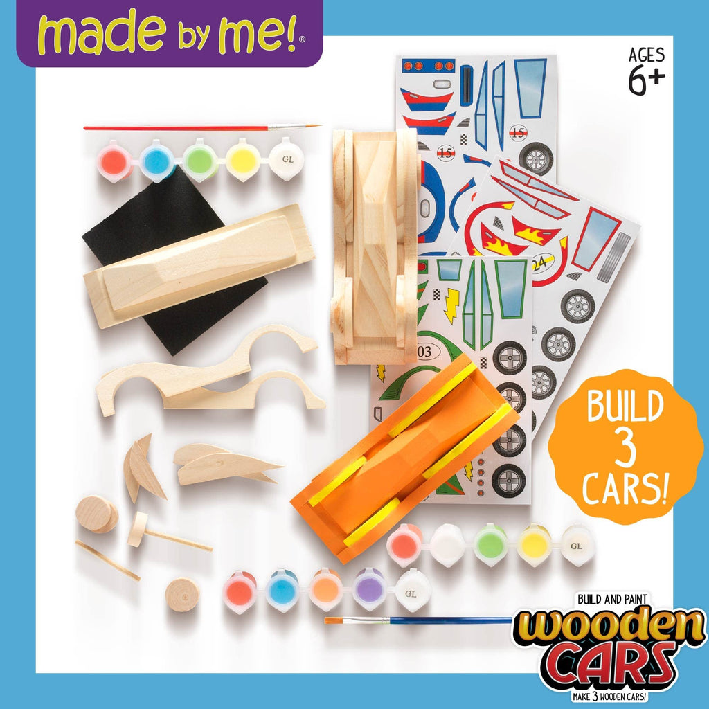 DIY wooden race car craft kit contents including wooden car parts, paint pots, brush, stickers, and sandpaper.