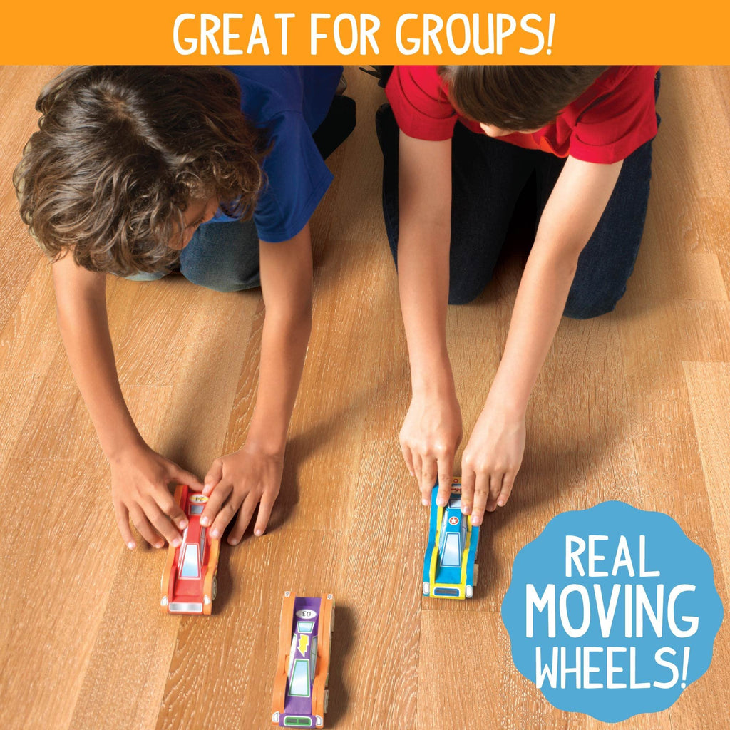 Two children playing with wooden race cars on a wooden floor, one car is red, one is blue and yellow, and one is purple and orange.