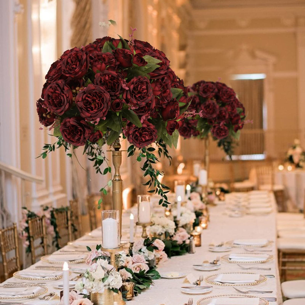 Burgundy artificial peony flower arrangements on a long table set for a wedding reception.