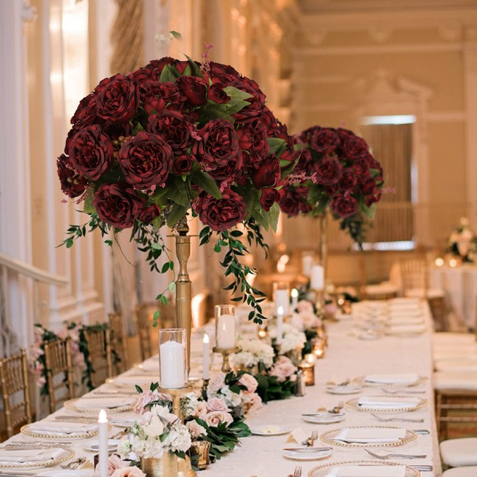 Burgundy artificial peony flower arrangements on a long table set for a wedding reception.