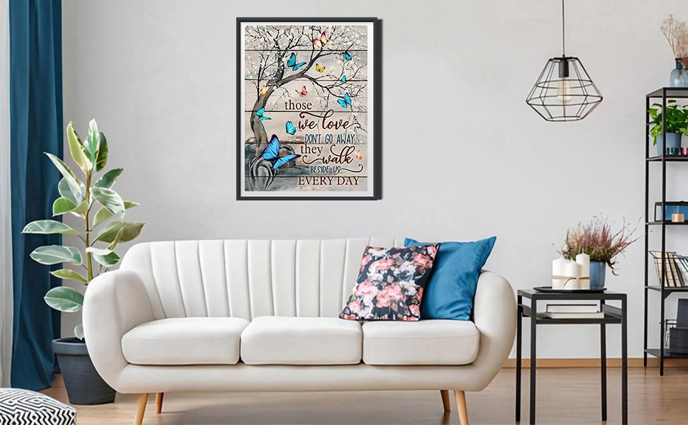 Diamond painting of a tree with butterflies and text about loved ones, framed and hanging on a wall above a sofa.
