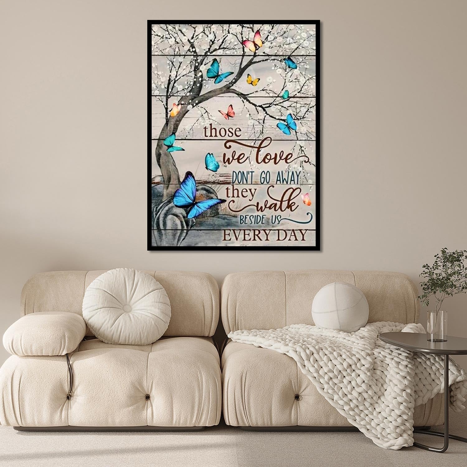 Diamond painting artwork of a tree with butterflies and inspirational quote on a wooden plank background, displayed above a sofa.