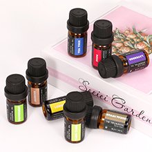 Assortment of small amber glass essential oil bottles with black caps, some upright and some on their sides, on a decorative surface.