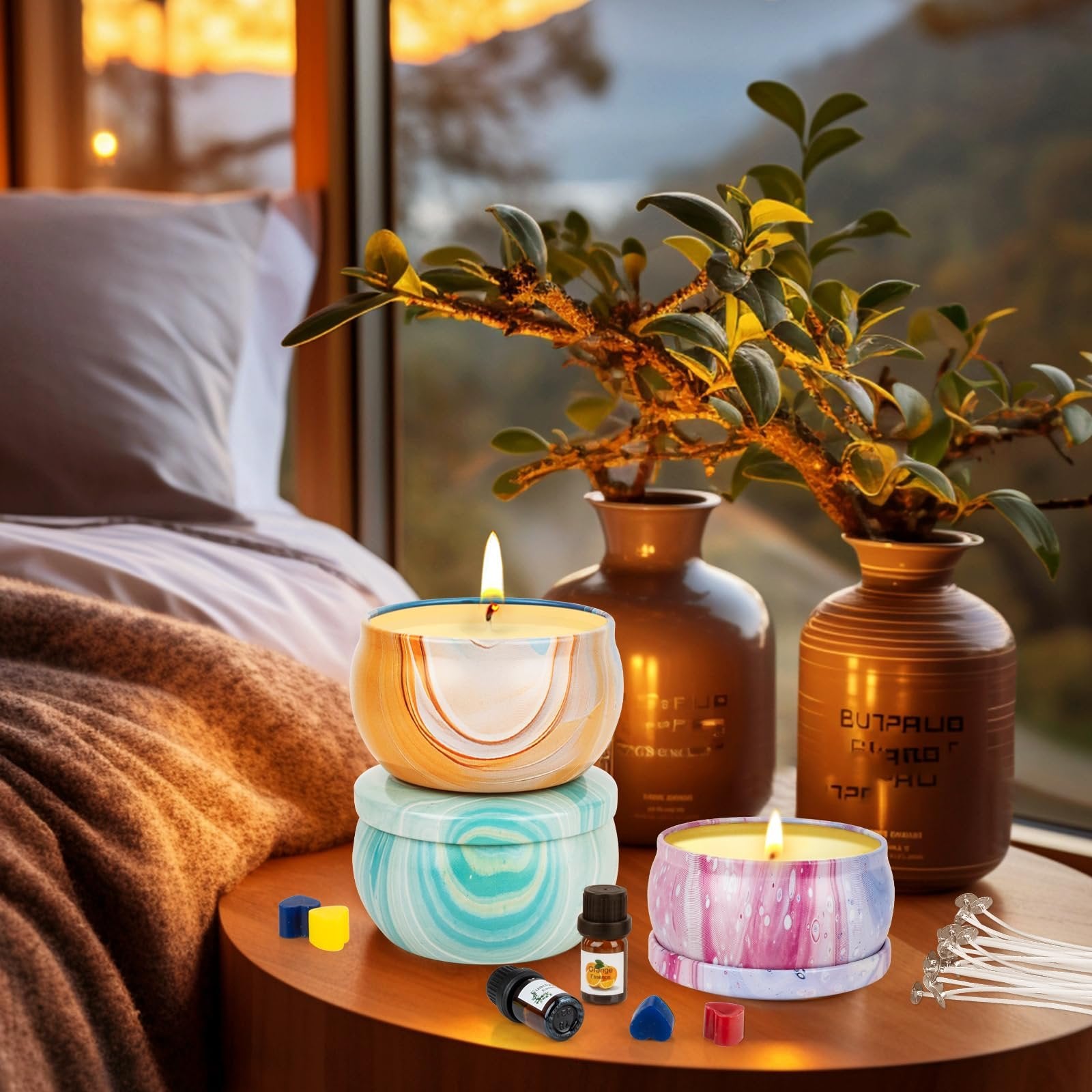 Three decorative candles in tins with swirling patterns, on a wooden table next to small wax blocks and essential oil bottles.