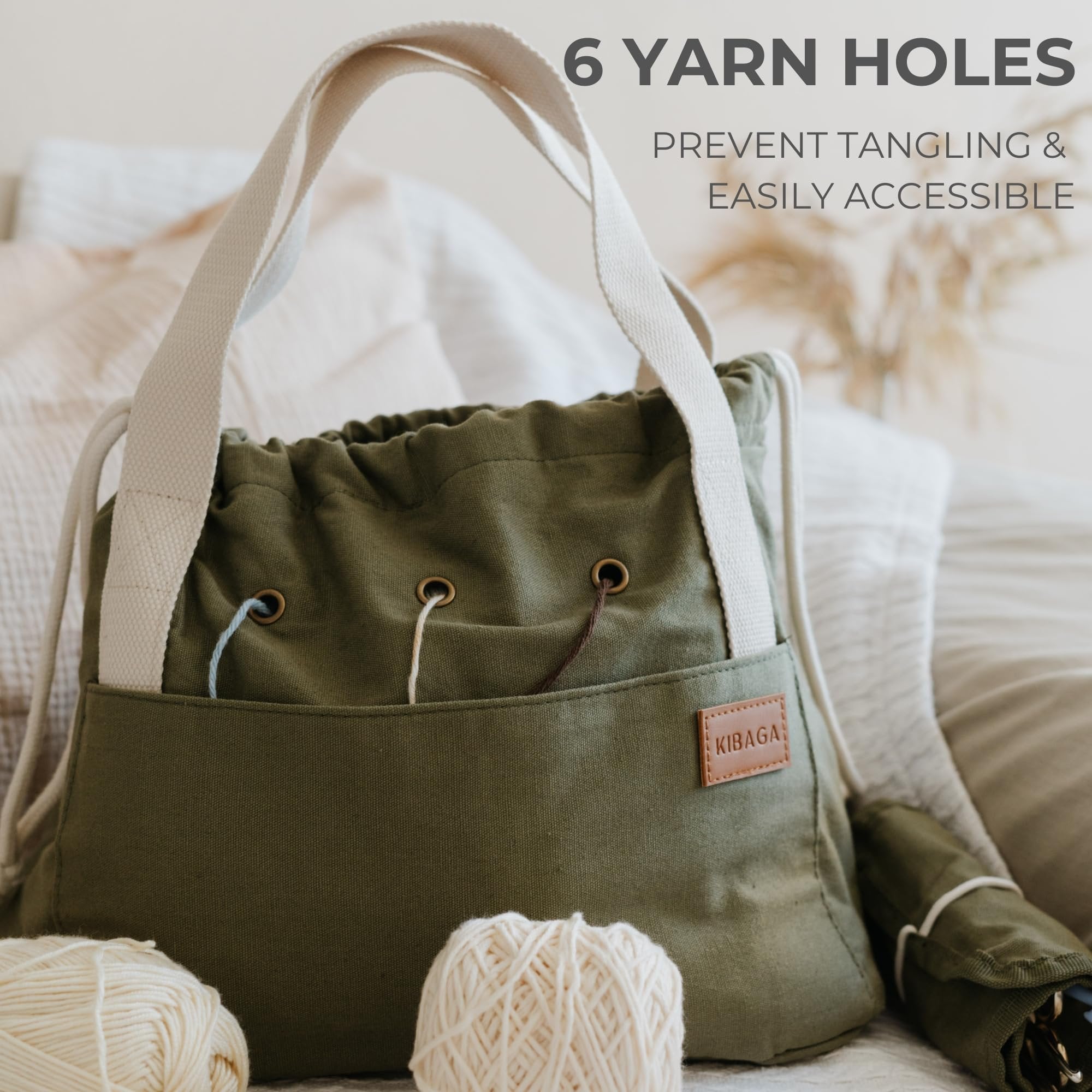 Olive green canvas crochet bag organizer with cream straps, showing yarn holes and a leather brand tag.