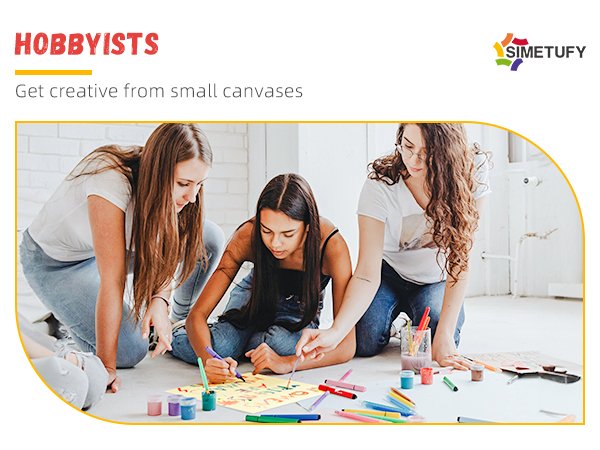 Three young women painting on canvases on the floor, surrounded by art supplies.