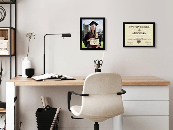 Graduation scene with a student in cap and gown and a framed diploma on a desk.