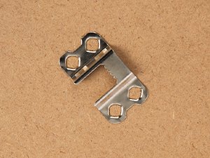 Metal sawtooth picture hanging hardware with screw holes on a wood-grain background