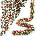 Champagne artificial rose vine garland with green leaves, displayed in hanging and coiled arrangements on a white background.