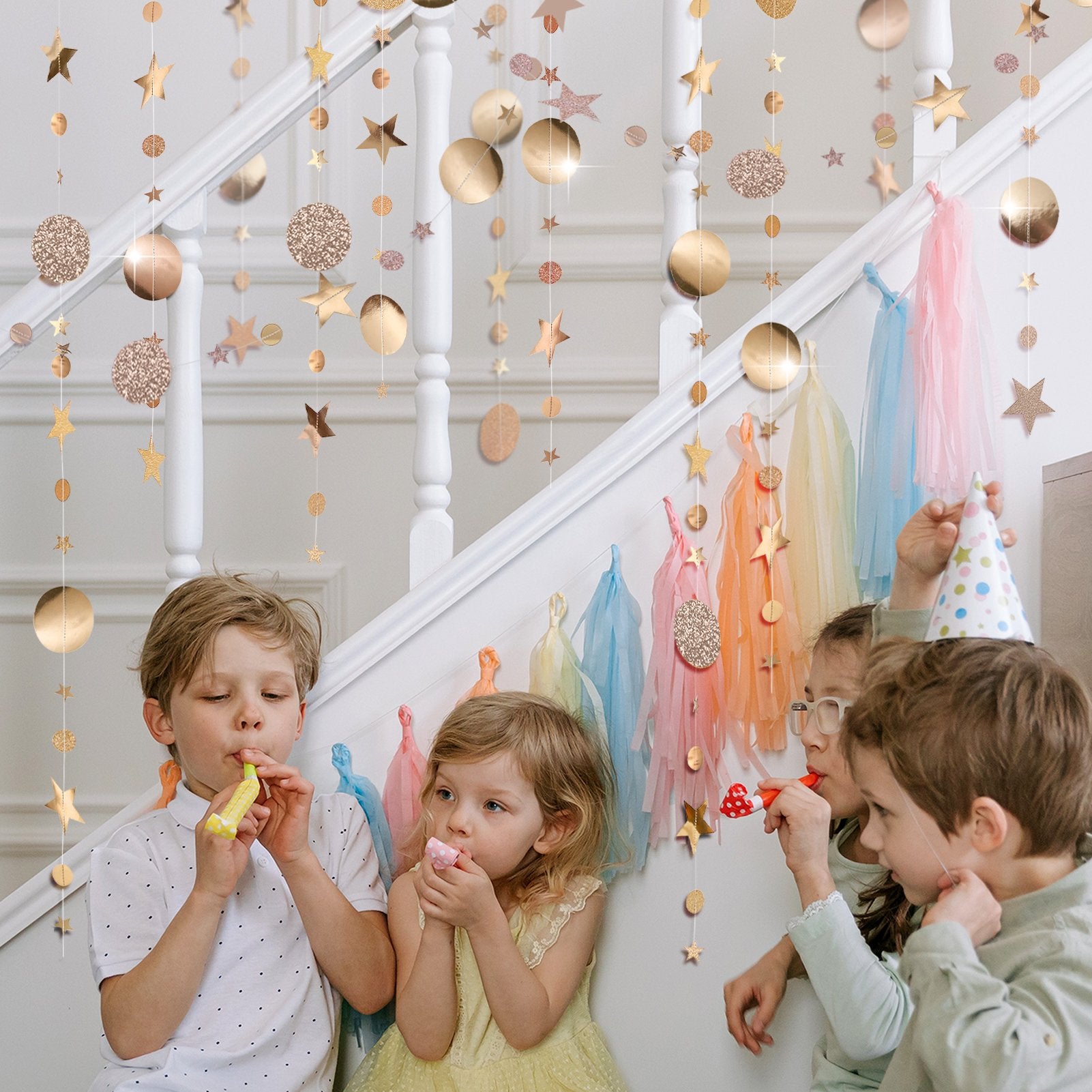Children celebrating with champagne gold star and circle garlands hanging on a staircase railing