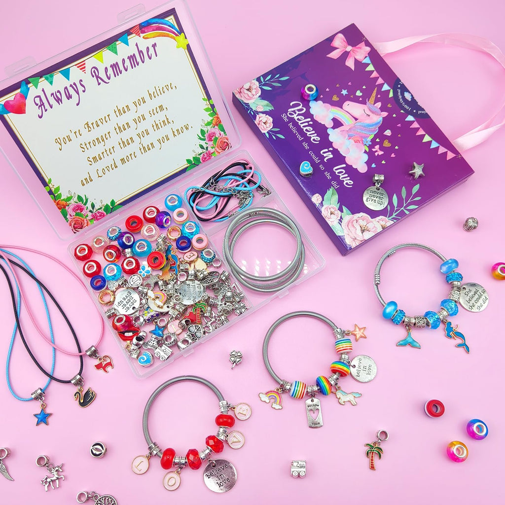 Charm bracelet making kit contents including beads, charms, cords, and bracelets laid out on a pink background.