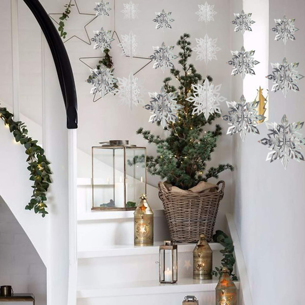 Hanging 3D paper snowflakes and a small Christmas tree on a staircase with lanterns and garland