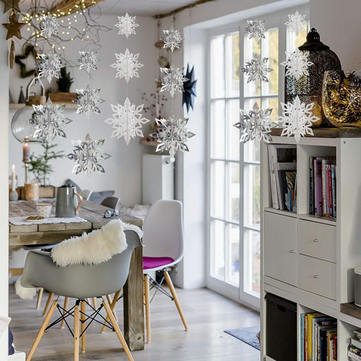 Hanging 3D paper snowflake ornaments in white and silver decorate a dining room for Christmas.