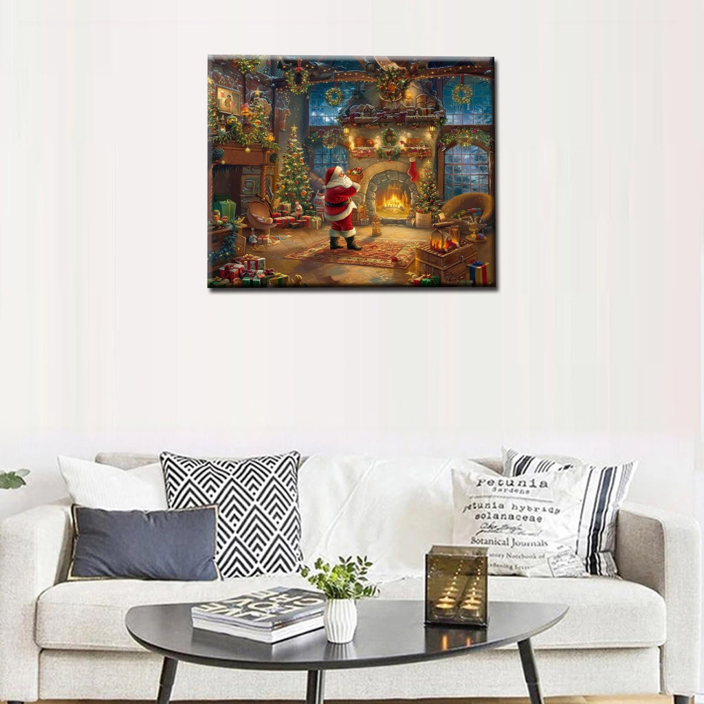 Christmas scene painting with Santa Claus by a fireplace and Christmas tree, displayed on a wall above a sofa.