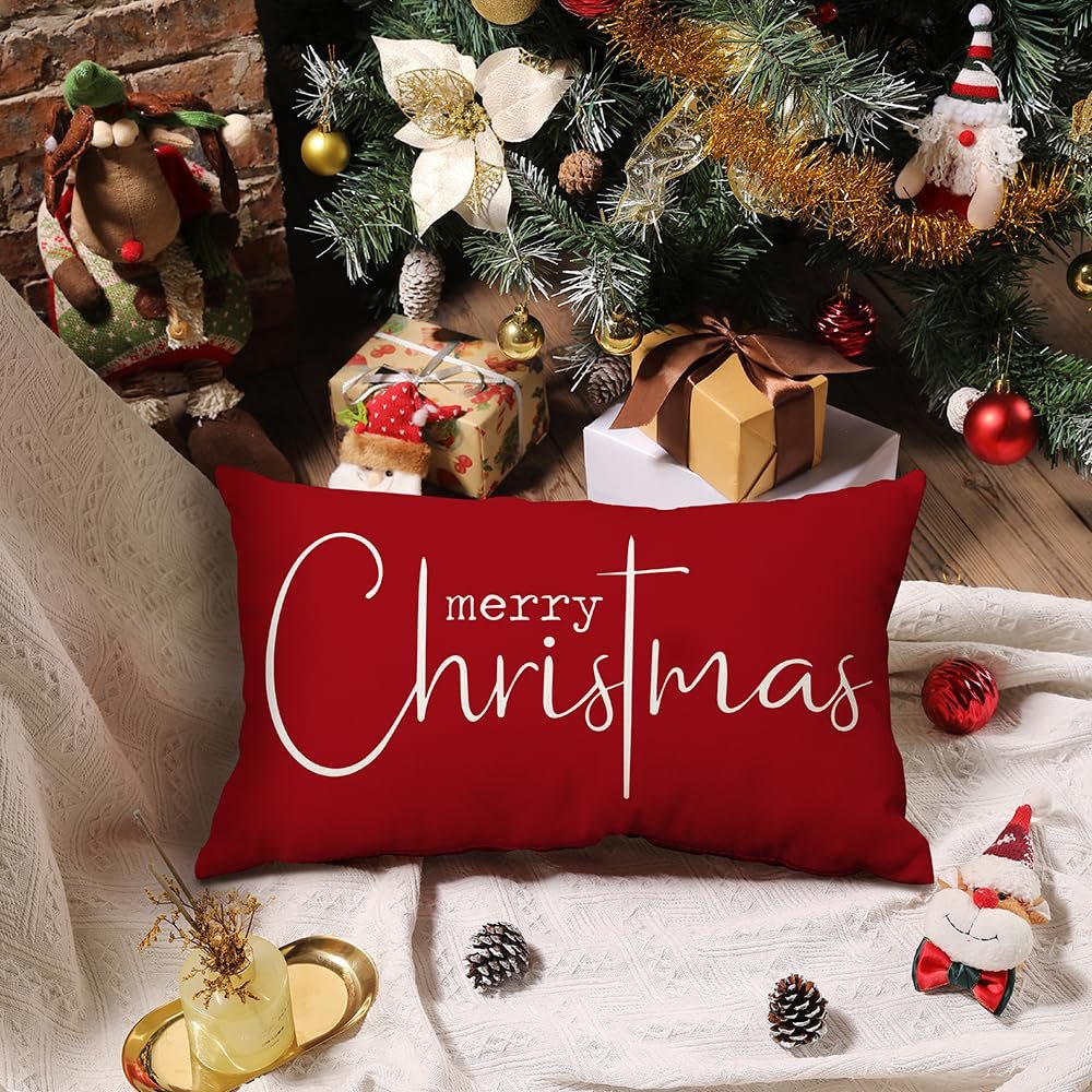Red rectangular Christmas pillow cover with white "merry Christmas" text, set against a festive backdrop with gifts and a Christmas tree.