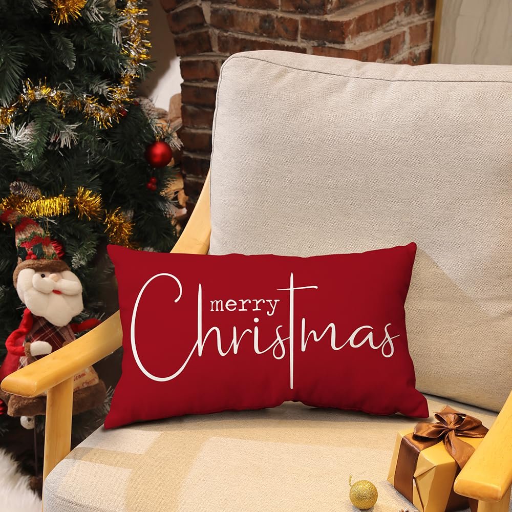 Red rectangular Christmas pillow cover with white 'merry Christmas' text, on a chair next to a Christmas tree.