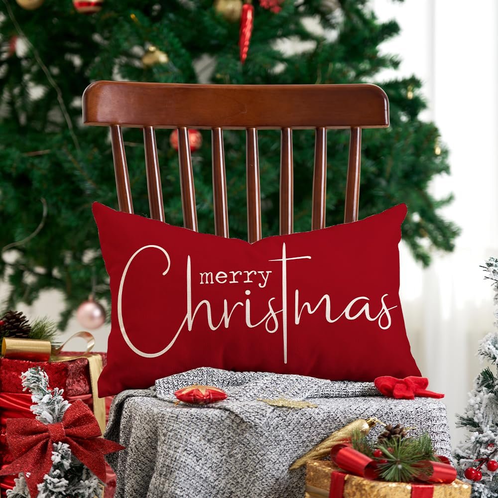 Red rectangular Christmas pillow with 'merry Christmas' text, placed on a chair with a Christmas tree background.
