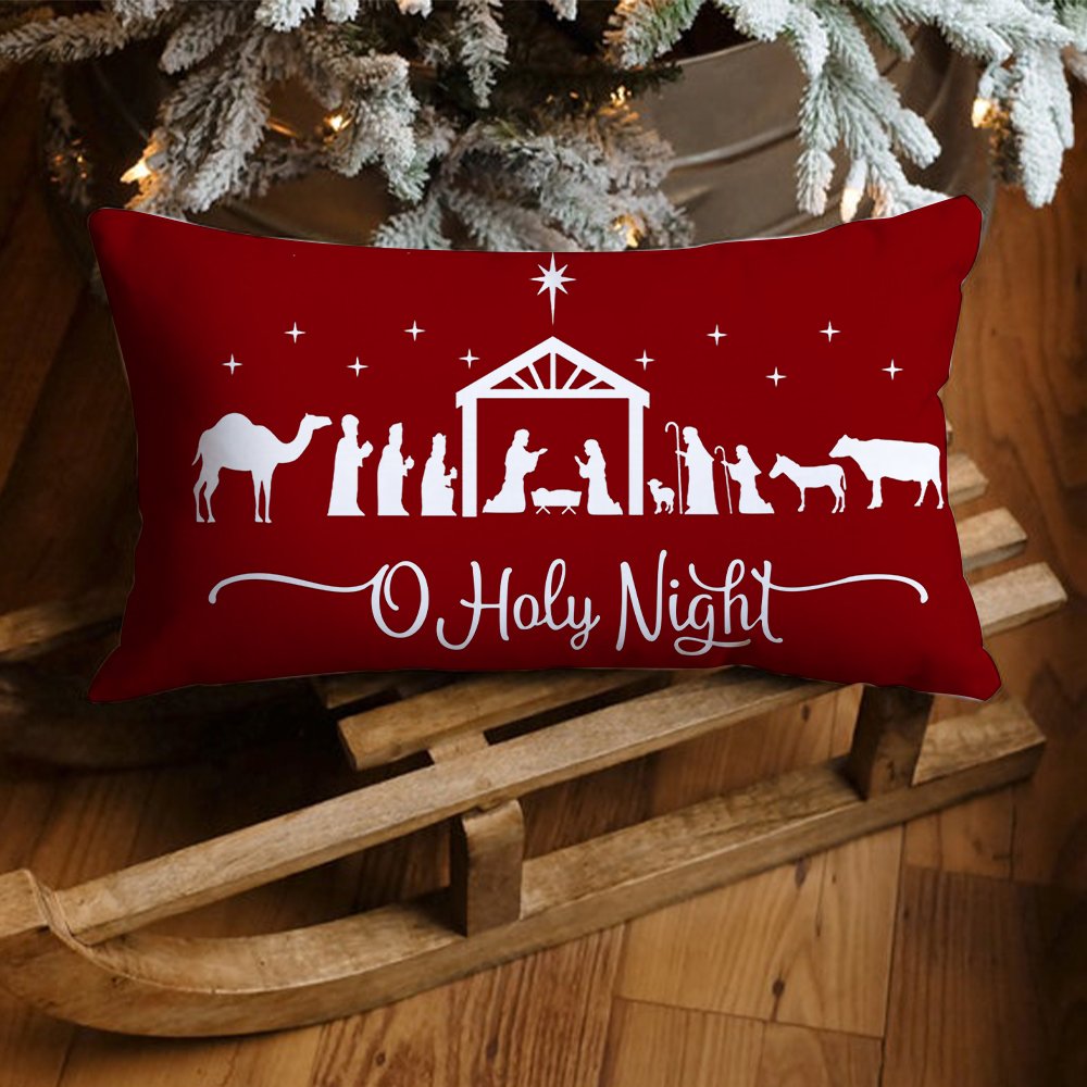 Red Christmas pillow cover with nativity scene silhouette and 'O Holy Night' text, resting on a wooden sled with a frosted tree in the background.
