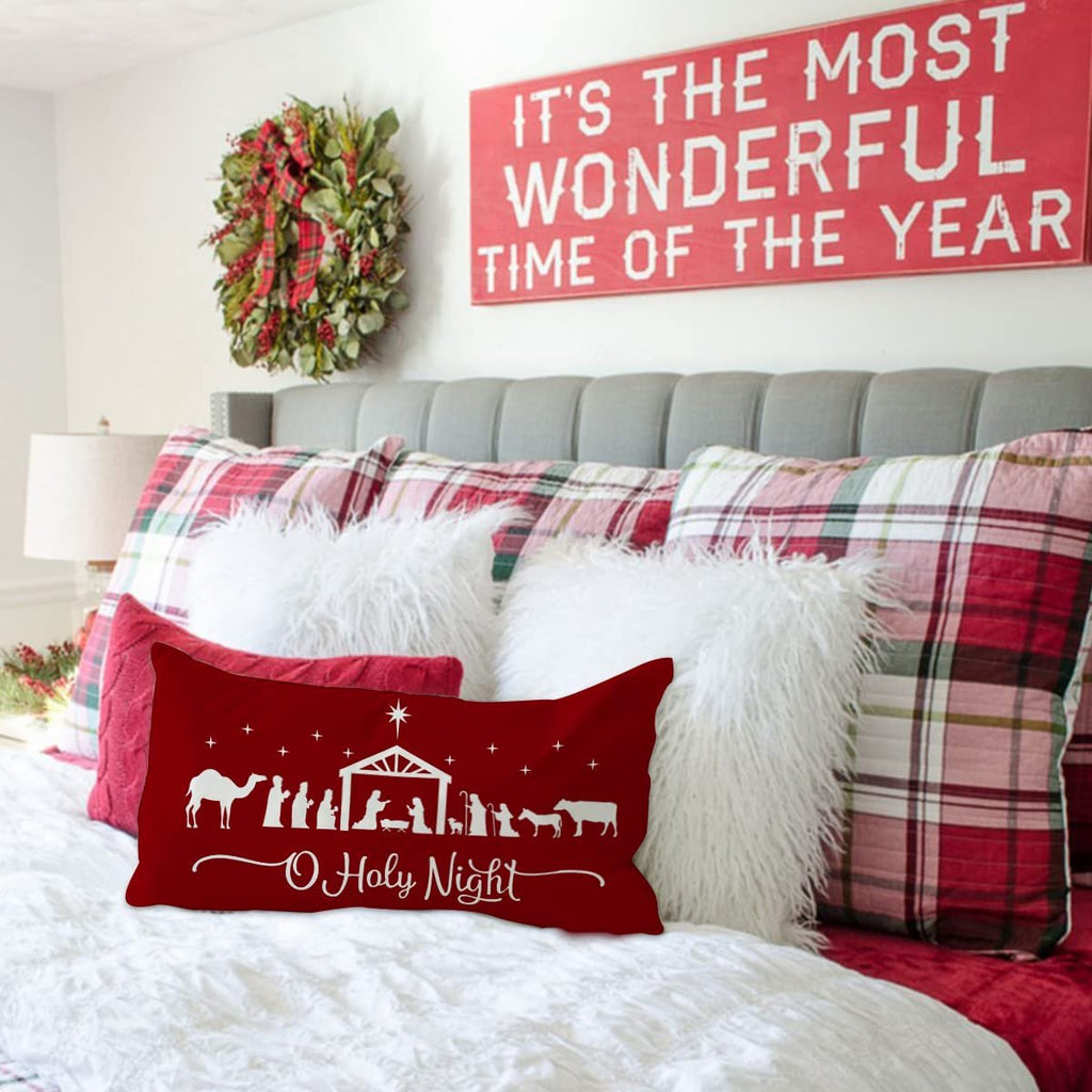 Red Christmas pillow cover with nativity scene and 'O Holy Night' text on a bed with plaid pillows