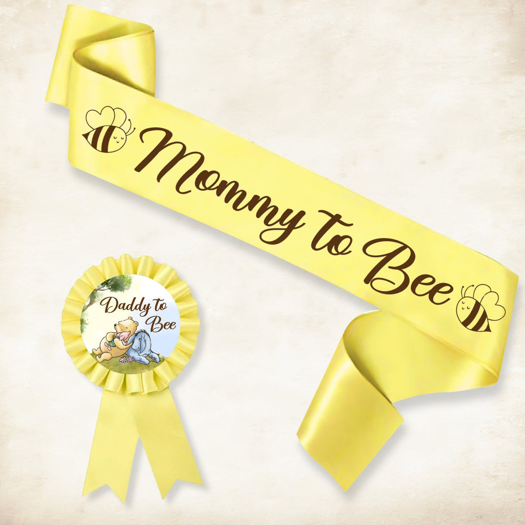 Yellow 'Mommy to Bee' sash and 'Daddy to Bee' rosette with Winnie the Pooh characters for a baby shower.