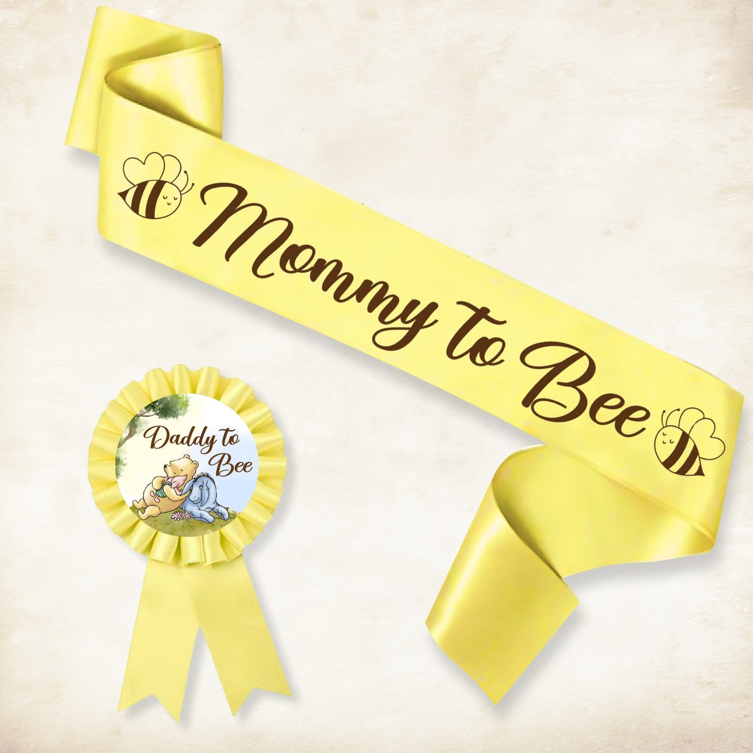 Yellow 'Mommy to Bee' sash and 'Daddy to Bee' rosette with Winnie the Pooh characters for a baby shower.