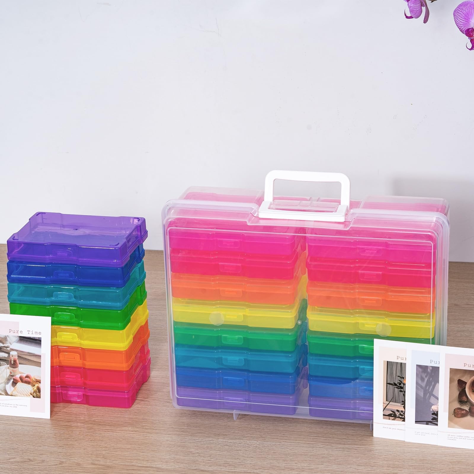 Stack of rainbow-colored photo storage cases and a larger clear case filled with rainbow cases, on a wooden surface.