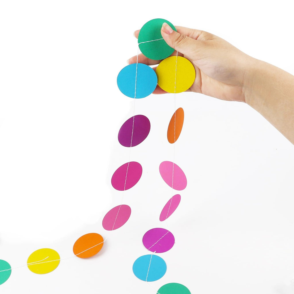 Hand holding colorful circle dot paper garland with rainbow colors on white background