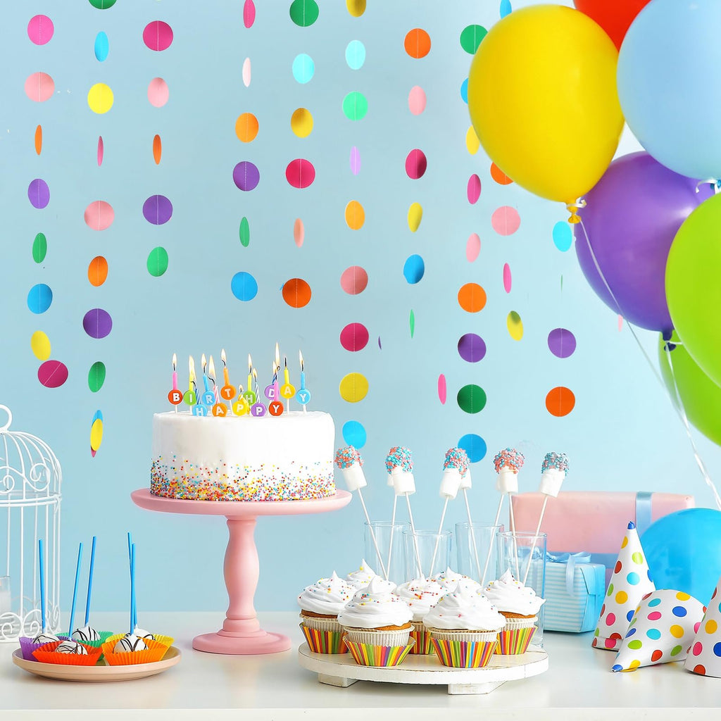 Birthday party scene with a cake, cupcakes, marshmallows, balloons, and colorful polka dot garlands against a light blue background.